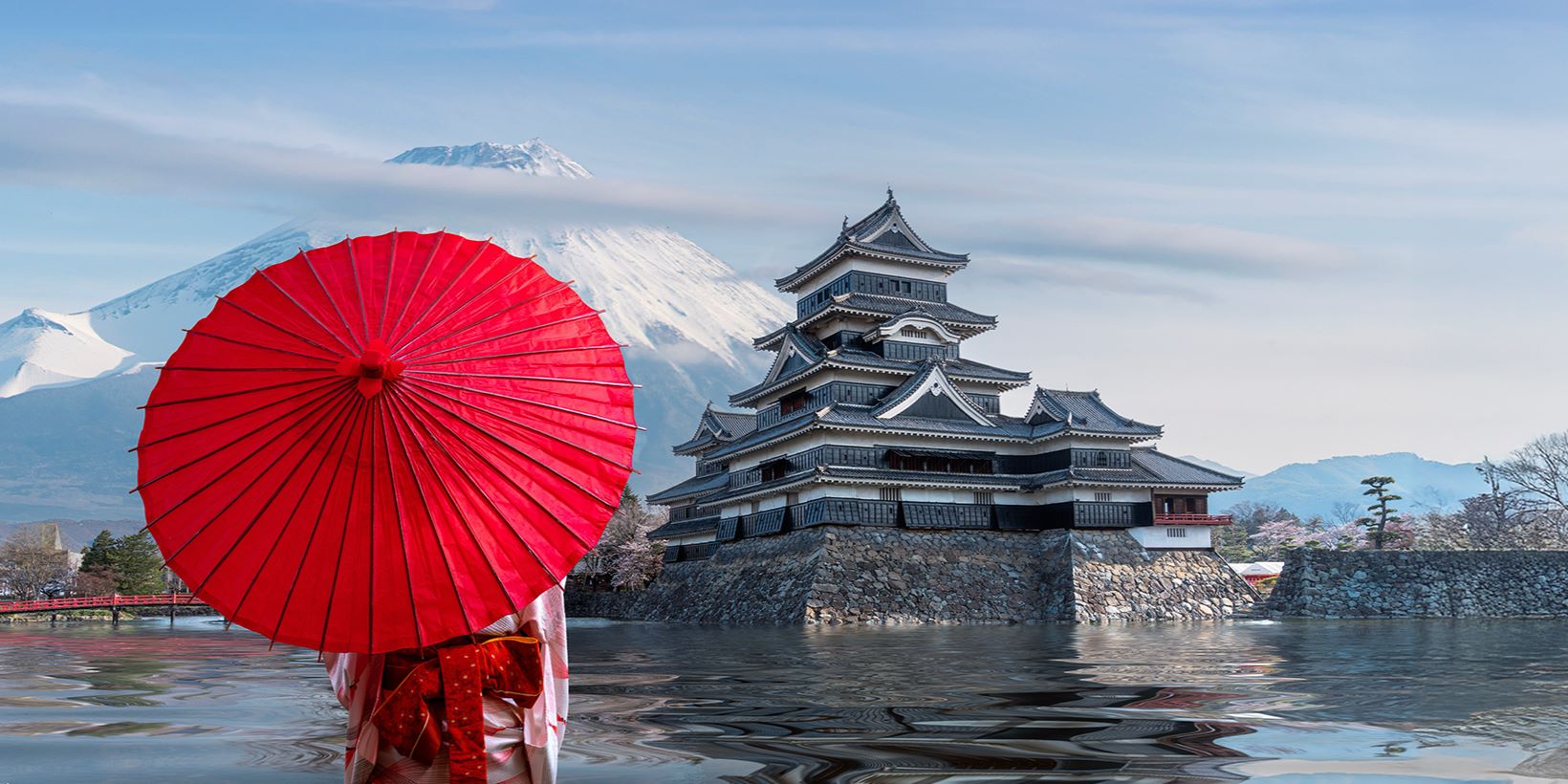 person with red umbrella facing pagoda and mountain