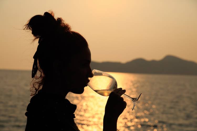 Beautiful woman drinking a glass of white wine, at sunset.