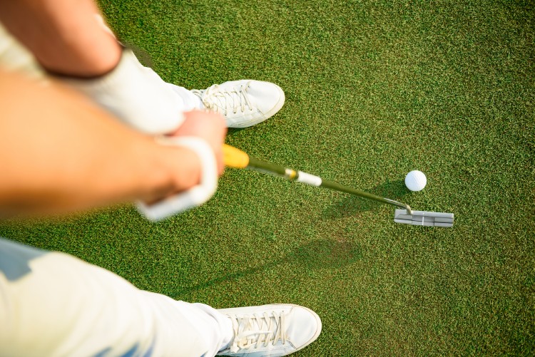 Driving it to the green. Top view of golfer hitting driver club on course for tee shot.