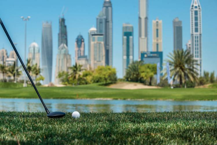 Golf ball lying on the grass in front of Dubai skyscraper