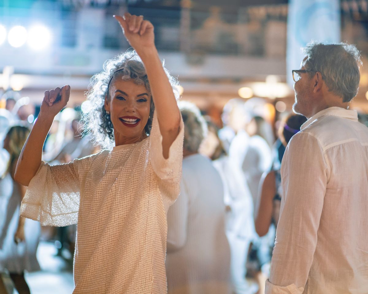 woman dancing in a crowd dressed in white